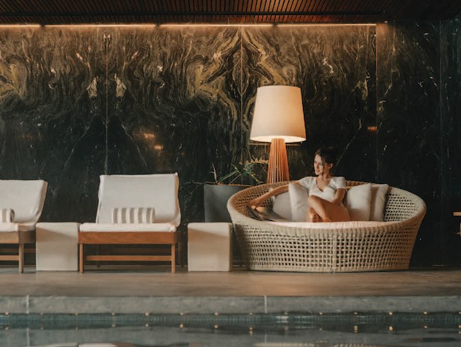 mulher sentada em cadeira ao lado da piscina